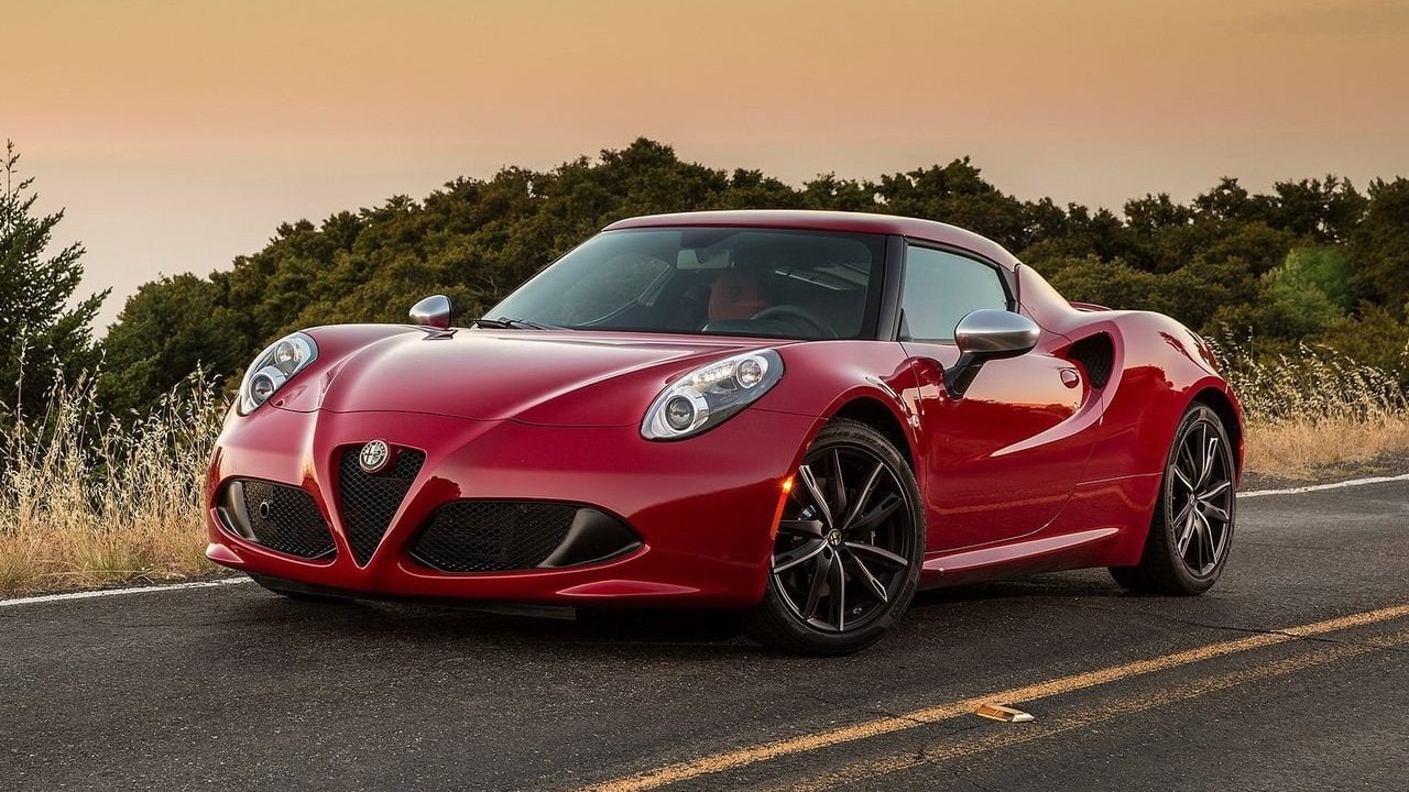 Vue 3/4 avant et latérale de l'Alfa Romeo 4C garé en bord de route avec coucher de soleil