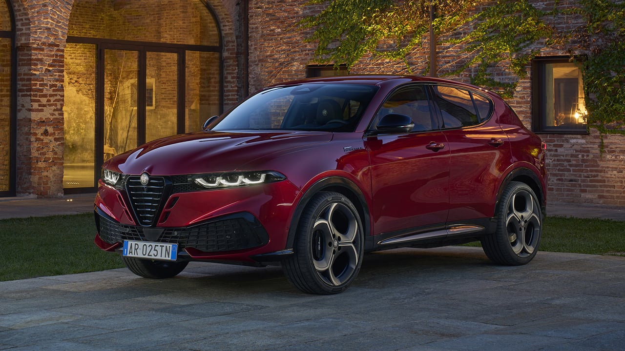 Vue 3/4 avant et latérale du Alfa Romeo Tonale 2026, stationné devant un batîment de pierre éclairer