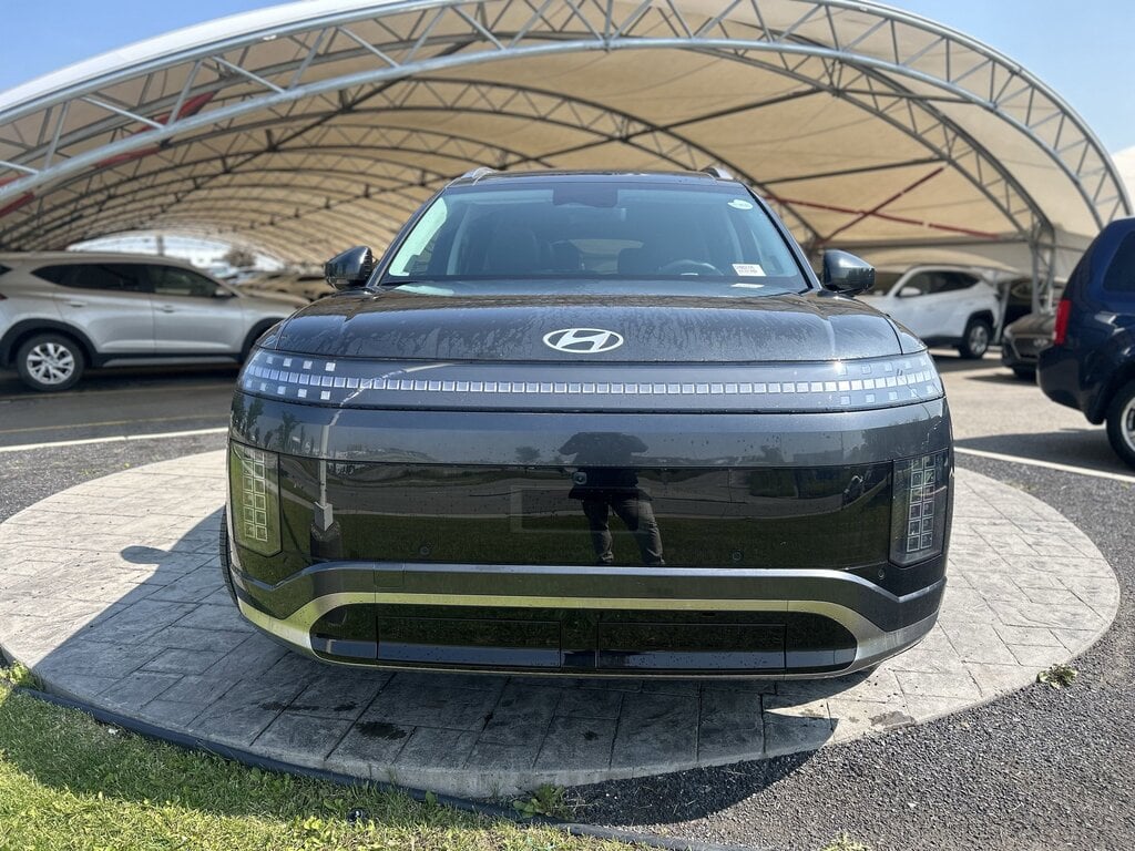 The close-up image features the front end of the 2026 Hyundai IONIQ 9, showcasing its distinctive pixel LED headlights and sleek aerodynamic grille design. This modern electric vehicle exemplifies Hyundai's commitment to innovative exterior design and advanced technology.