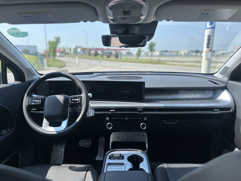 The image shows the interior of the 2026 Hyundai IONIQ 9, featuring a spacious flat floor cabin with three rows of seating, including second row and third row seats. The design emphasizes comfort with relaxation seats and a panoramic sunroof, creating an inviting atmosphere for all passengers.