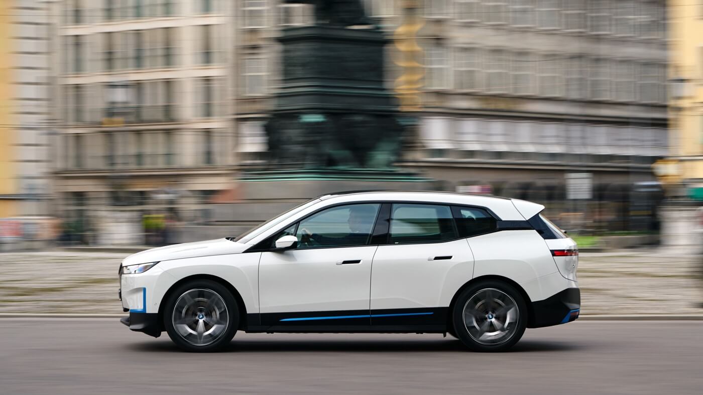 side view of a white BMW iX xDrive40 SUV driving in a city