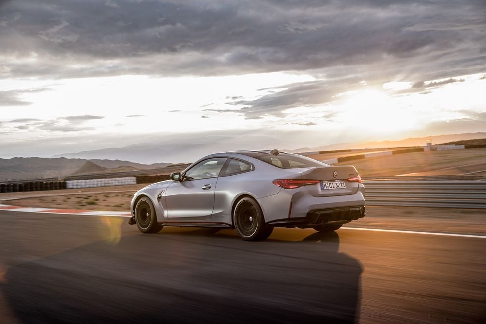 rear side view of a 2023 BMW M4 on a race track at dusk