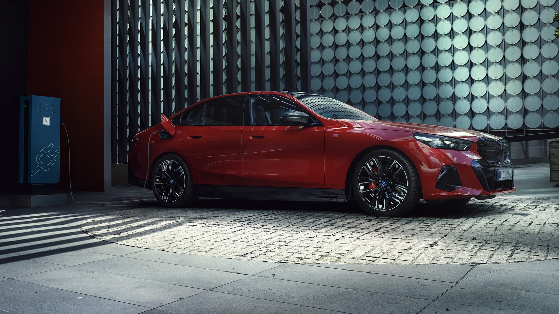 The BMW M60 2025 being recharged in front of a residence.