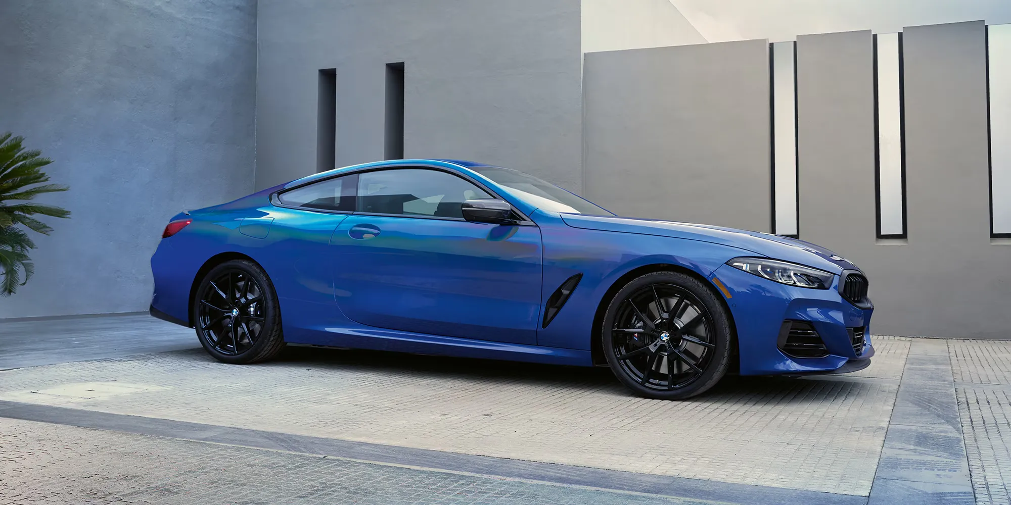 Blue 2025 BMW M850i Coupé parked, highlighting the grille and aerodynamic body lines.