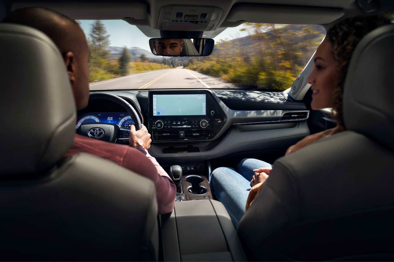 A couple drives a vehicle, showing the interior view of the car.