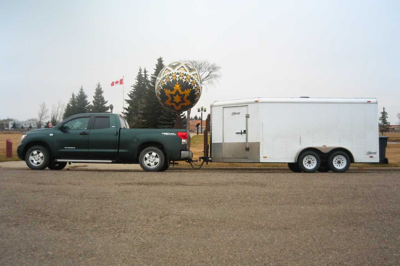 A Toyota Tundra pulling a trailer, stands in front of the Vegreville Pysanka Easter Egg statue.