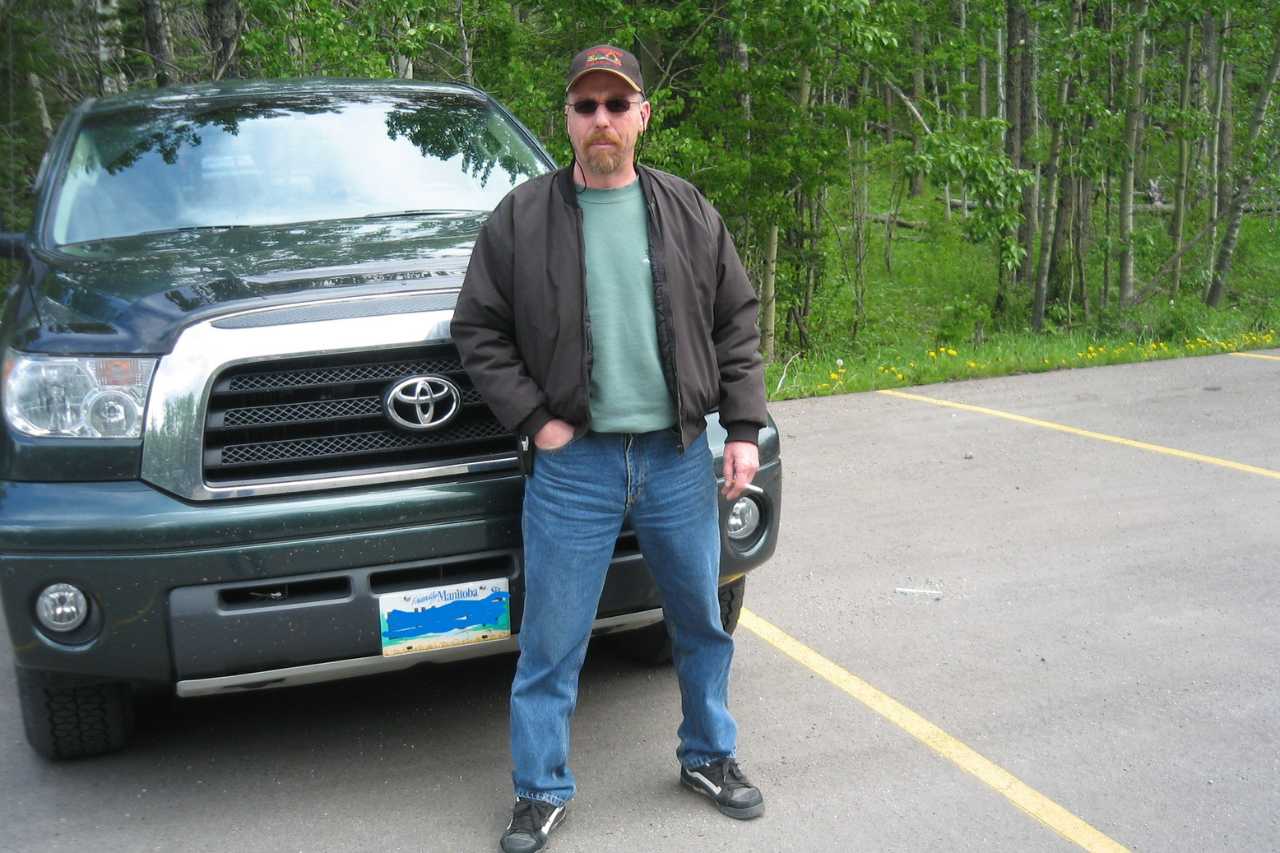 Arthur standing in front of his Toyota Tundra, with a green forest in the background.