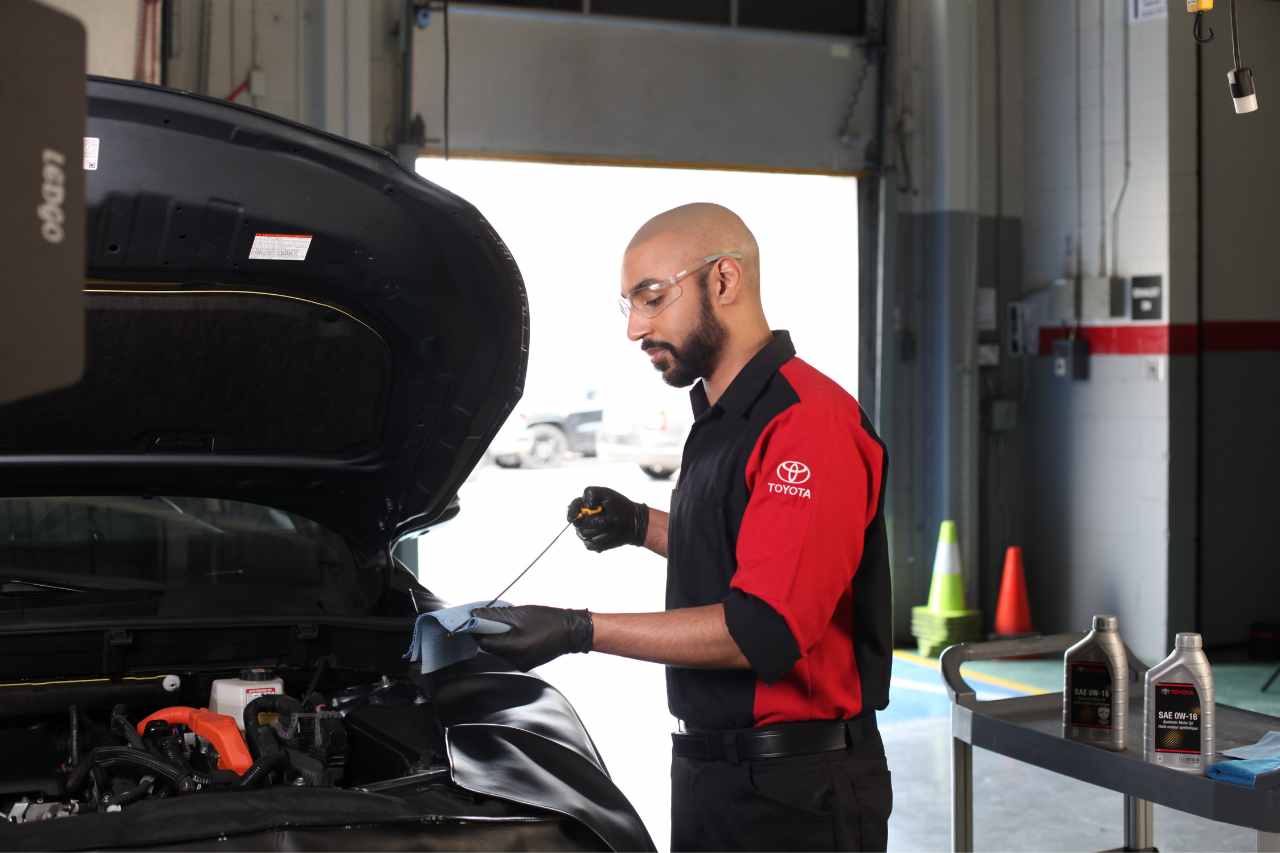 A Toyota Service technician checks the dipstick for oil levels during an oil change.