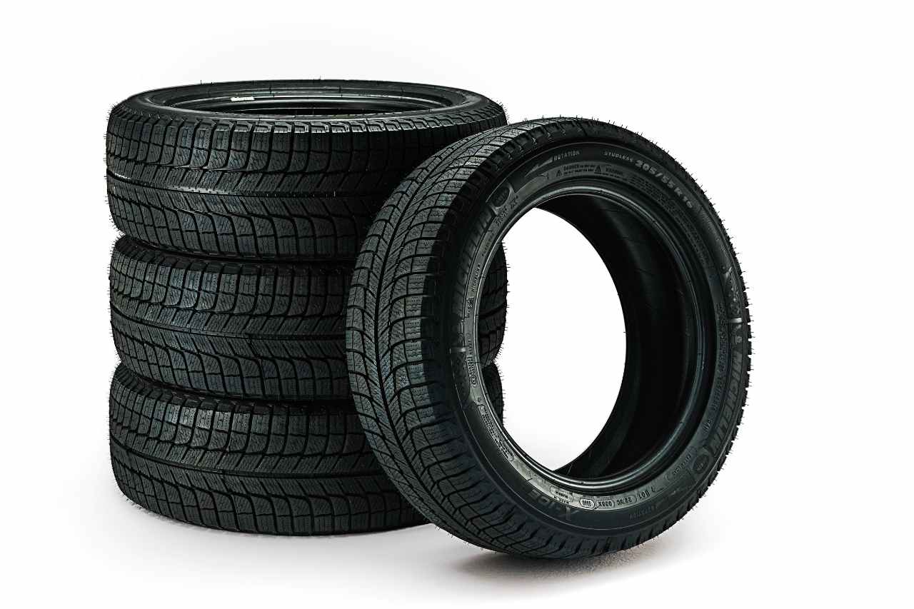 A photo of Toyota tires on a white background, with a stack of three tires laying on the ground, and one tire propped up against the stack.