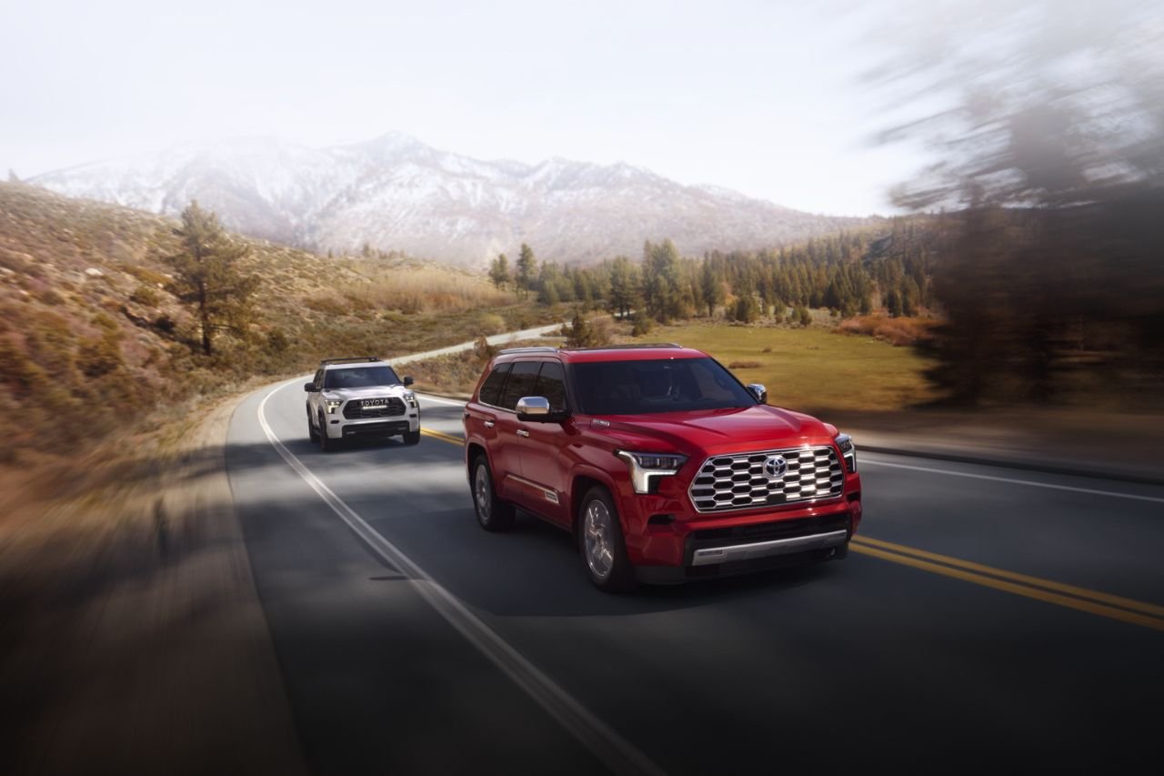 Two brand new Toyota Sequoia SUVs drive down a mountain highway.
