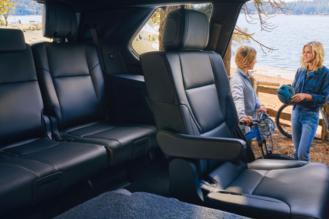 A mother and daughter stand outside their 3-row SUV, with the 2nd and 3rd rows clearly displayed.