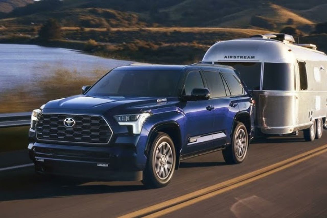 The 2025 Toyota Sequoia in a blue colour tows a trailer on a camping trip.