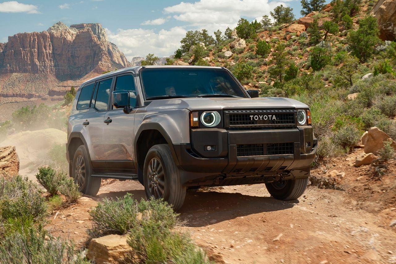 The adventurous off-roading SUV, the Toyota Land Cruiser, explores a sunny desert among cacti and shrubs.