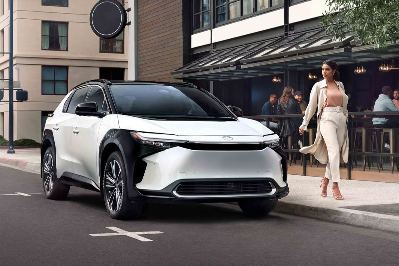 A woman walks past her white 2025 Toyota bZ4X electric vehicle.