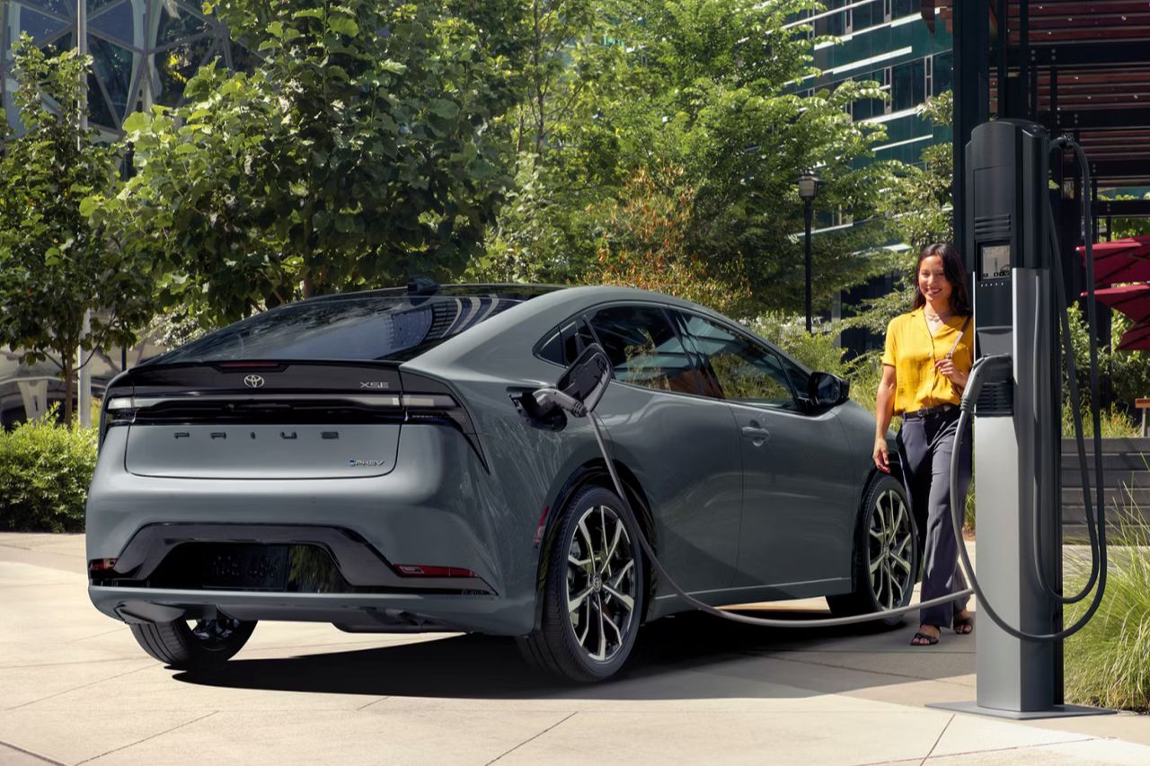 A woman plugs a charger into a grey 2025 Toyota Prius Plug-In Hybrid. 