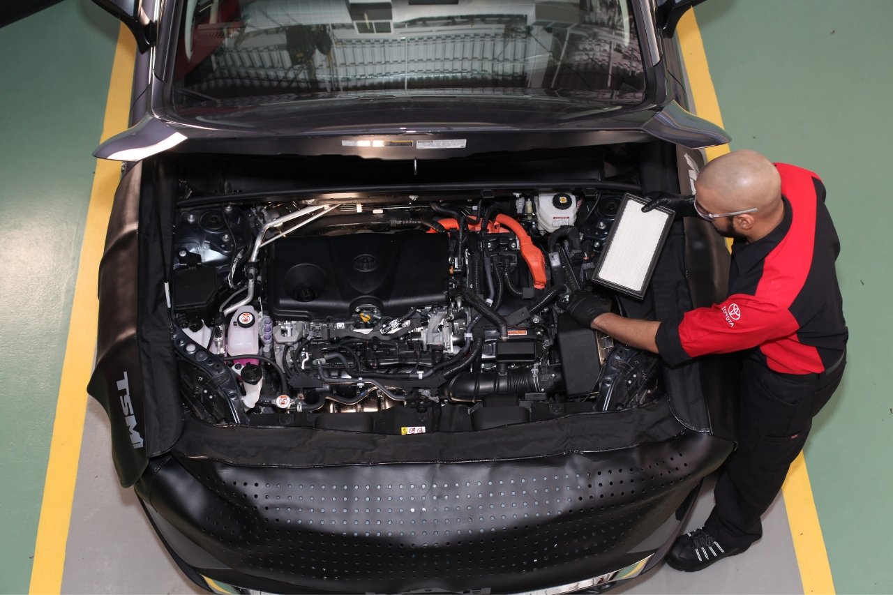 A Toyota service technician lifts up the hood of a vehicle during a service inspection.