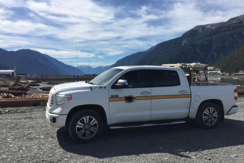 Jason's white work truck, outfitted with work gear, is parked on the side of a worksite.