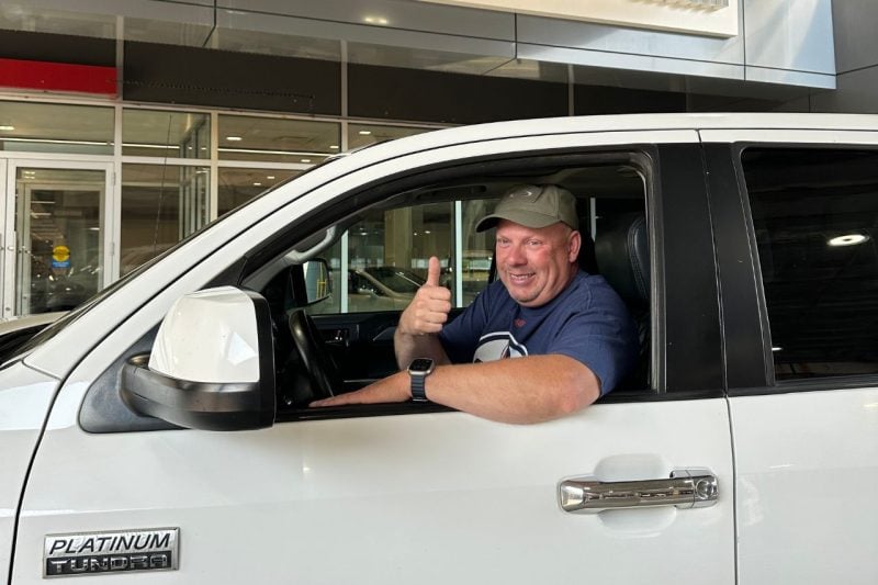 Jason smiles and gives a thumbs up while sitting in the drivers seat of his truck.