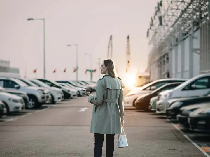 Driver walking through parking lot with phone